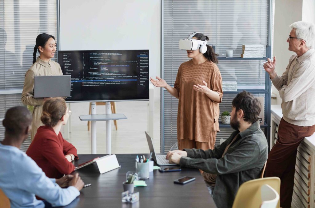 Portrait of diverse IT development team working on virtual reality software, focus on smiling woman wearing VR headset in office